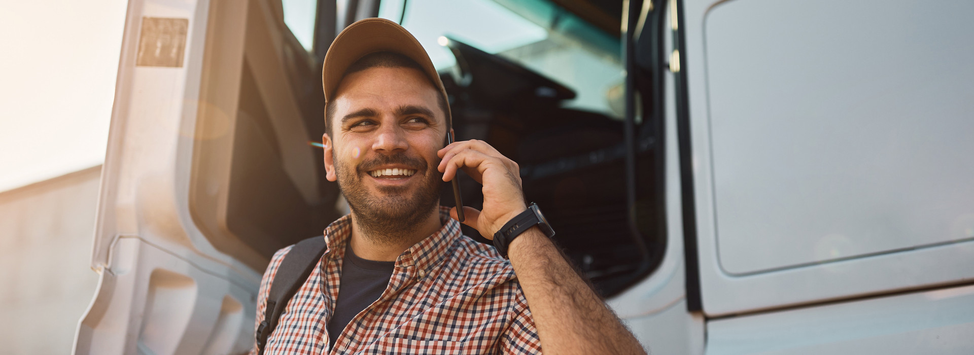 Driver has parked the truck and is speaking on the smart phone with a smile in his face